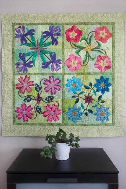 Bright and colourful. Machine applique and maching quilted. Fabric on back is a beautiful dragonfly pattern on blue clouds.50" square. (Hanging pocket on back).           $150.00